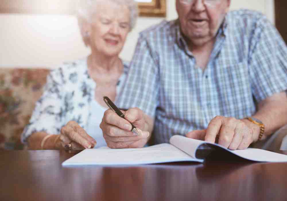 Elderly couple signing documents at home on Cape Cod MA